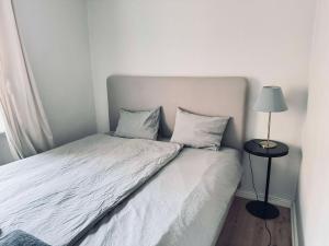 a bed with white sheets and a lamp on a table at Spacious flat for large group in Stockholm