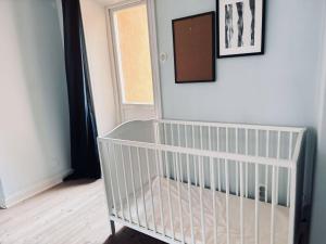 a white crib in a room with a window at Spacious flat for large group in Stockholm