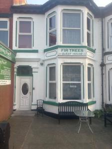 a white house with a bench in front of it at Fir Trees in Blackpool