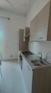 een keuken met een wastafel, een fornuis en kasten bij Casa Olga in La Spezia