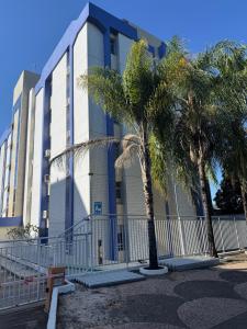 een gebouw met palmbomen ervoor bij Loft moderno e aconchegante próximo ao Aeroporto, Rodoviária Interestatual, P Federal, Casv da Empaixada - Brasília in Brasilia