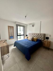 een slaapkamer met een blauw bed en een groot raam bij Departamentos Céntricos Exclusivos in Villa Carlos Paz +45 foto's