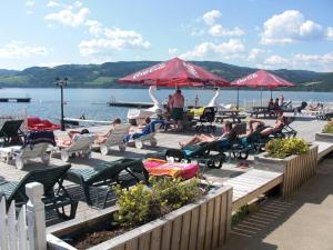a group of people sitting on a dock with chairs and umbrellas at Steinvik Camping in Moelv