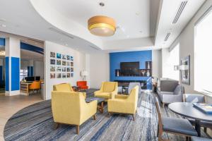 a lobby with chairs and tables and a tv at Holiday Inn Express & Suites Downtown Louisville by IHG in Louisville