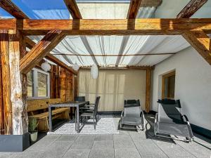 eine Terrasse mit einem Tisch und Stühlen in einem Zimmer in der Unterkunft Alpine Apartment Goldquell - Infrarot Kabine, National Park Sommerkarte und Bergblick in Rauris
