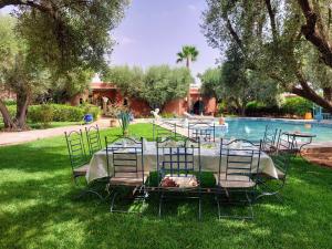 a table and chairs in the grass next to a pool at Dar HISANE in Marrakesh