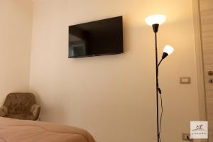a bedroom with a tv on the wall and a lamp at La casa di zia Maria in Pozzuoli