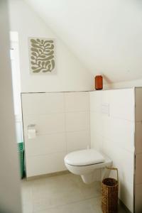 a white bathroom with a toilet and a basket at Ferienwohnung KÖÖK Küstentraum - Modern, Balkon, Strandnah, Maisonette in Neuharlingersiel +20 photos