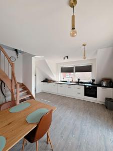 a kitchen with a wooden table and a dining room at Ferienwohnung KÖÖK Küstentraum - Modern, Balkon, Strandnah, Maisonette in Neuharlingersiel