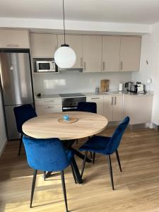 eine Küche mit einem Holztisch und blauen Stühlen in der Unterkunft Apartament Playa Gandia - nowy apartament z basenem, 350 m od plaży in Playa de Gandia