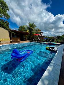 a swimming pool with two inflatables in the water at Condomínio Ouro vilas in Arraial d'Ajuda