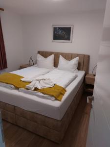 ein Bett mit weißer Bettwäsche und einer gelben Decke darauf in der Unterkunft APPARTEMENT 305 - Natur & SPA - Ponyhof & Streichelzoo - #allgäuresidenz in Wiggensbach