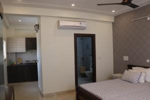a bedroom with a bed and a kitchen with a ceiling fan at Little Sparrow Home Stay in Rishīkesh