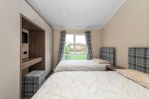 a bedroom with two beds and a window at Stables 30, 3 Bed Luxury Lodge at Hafan y Mor in Pwllheli