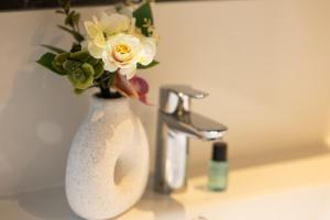 a white vase with flowers sitting on a bathroom sink at Fewomo - Moseltraum ! Exklusive Unterkunft für Genießer - Nah am Schloss in Lieser