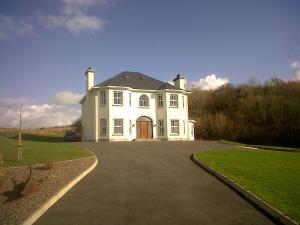 ein großes weißes Haus mit Auffahrt in der Unterkunft Rosswood House in Donegal