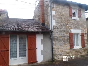 ein altes Backsteingebäude mit roten Türen und Fenstern in der Unterkunft chambre chez l'habitant chez myriame in Eurville