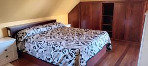 a bedroom with a bed with a black and white comforter at Casa San Roque in Villanueva de Arosa