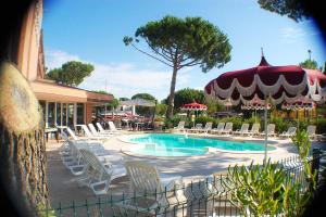 a swimming pool with lounge chairs and a restaurant at Hotel Riva dei Cavalleggeri in Marina di Bibbona