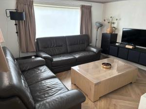 a living room with a leather couch and a coffee table at Vakantiechalet Tip 30 op vakantiepark de Heische Tip in Zeeland