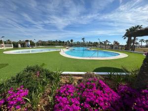 a swimming pool in a yard with purple flowers at Casa Felicita Playa Azul in El Borseral