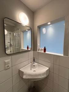 a white bathroom with a sink and a mirror at Lago mio - Pension am See - bei uns verbringt Ihr eine wundervolle Zeit direkt am Wasser in Wörthsee +22 photos