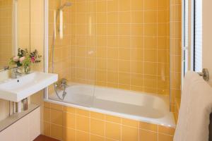 ein gelb gefliestes Bad mit einer Badewanne und einem Waschbecken in der Unterkunft Family Residence in Paris