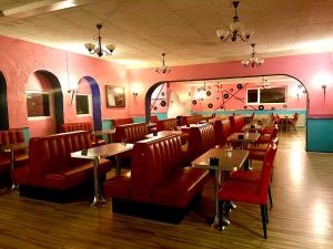 a restaurant with red chairs and tables in a room at Café Retro Brøns Kro in Skærbæk