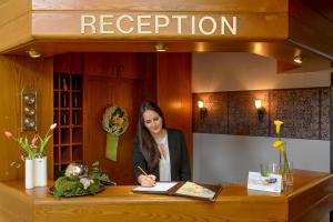 a woman sitting at a table with a book at Hotel am Brenner in Tauberbischofsheim
