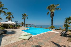 a swimming pool with palm trees and the ocean at Talizeti Home - Adults Only in Sarti