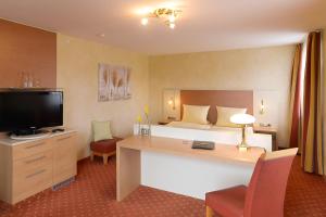 a hotel room with a bed and a desk with a television at Hotel am Brenner in Tauberbischofsheim