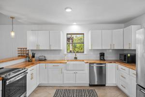 a white kitchen with white cabinets and a window at 6 BR Hot Tub King Beds Game Room Tiled Showers in Fredericksburg