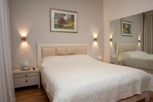 a bedroom with a white bed and two night stands at Caesarea Vacation Rooms in Caesarea +42 photos
