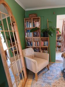 a room with a chair and book shelves with books at Sea Rose Cottage with Hot Tub in Dido Valley