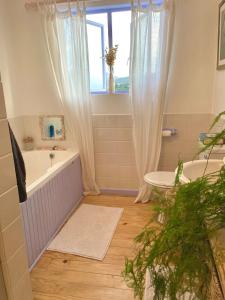 a bathroom with a tub and a sink and a window at Sea Rose Cottage with Hot Tub in Dido Valley