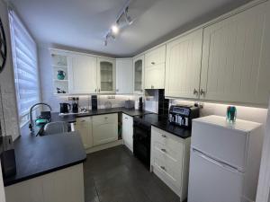 a kitchen with white cabinets and black counter tops at Happy Hinwood House, Hampshire! in Stockbridge