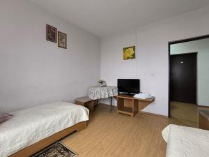 a room with two beds and a desk with a television at Pensiunea Daria in Căşeiu