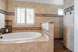 La grande salle de bains est pourvue d'une baignoire et d'une fenêtre. dans l'établissement King Beds Hot Tub On 290 Large Estate Kitchen, à Fredericksburg