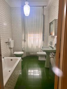 ein Badezimmer mit einer weißen Badewanne und grünem Boden in der Unterkunft Stanza 30 euro per 2 ore Giarre in Giarre