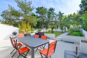 a patio with a table and orange chairs at Maison, 150 m de la plage, la Tresson,Noirmoutier in La Guérinière