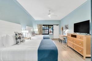 a hotel room with a bed and a flat screen tv at Beachside Inn in Destin