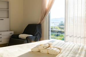 1 dormitorio con 1 cama con silla y ventana en Christo’s Beachfront Bliss, en Nafpaktos