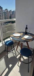 a table with two chairs and wine glasses on a balcony at The Palace Flat Moema 1210 in São Paulo