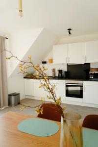 a kitchen with white cabinets and a table with a plant at Ferienwohnung KÖÖK Heimathafen - Modern, Balkon, Strandnah in Neuharlingersiel