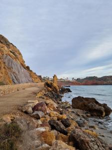 a beach with rocks and the ocean on a cloudy day at Casa del Mar in Puerto de Mazarrón