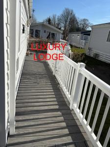 a wooden walkway leading to a house with a luxury lodge sign at Luxury lodge T11 in Hastings +42 photos