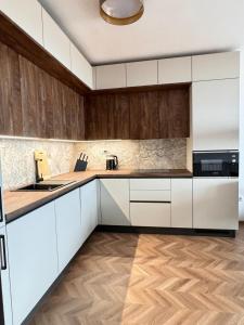 a kitchen with white cabinets and wooden floors at SeaView Etara IV Apartment in Sveti Vlas in Sveti Vlas