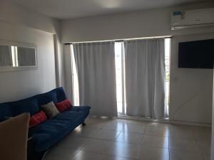 a living room with a blue couch and a large window at Comfortable Apartamento Semi Piso in Buenos Aires