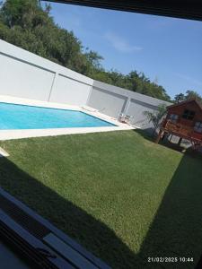 Blick auf einen Garten mit Pool in der Unterkunft ვႷჿʇⴝꞁƂϨȢʇ Casa- Quinta con Quincho y pileta, Equipada Completa, con Cochera Doble, 3Habit 2baños, para 7 Personas, Alquiler Temporal Ramallo- San Nicolás, WHATSAP AL ვႷჿʇⴝꞁƂϨȢʇ, CONSULTAR EL PRECIO REAL PARA RESERVAR EN PRIVADO in Estación Ramallo