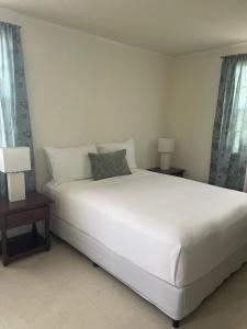 une chambre avec un grand lit blanc et deux lampes dans l'établissement Jo'Marion's Place, à Saint James